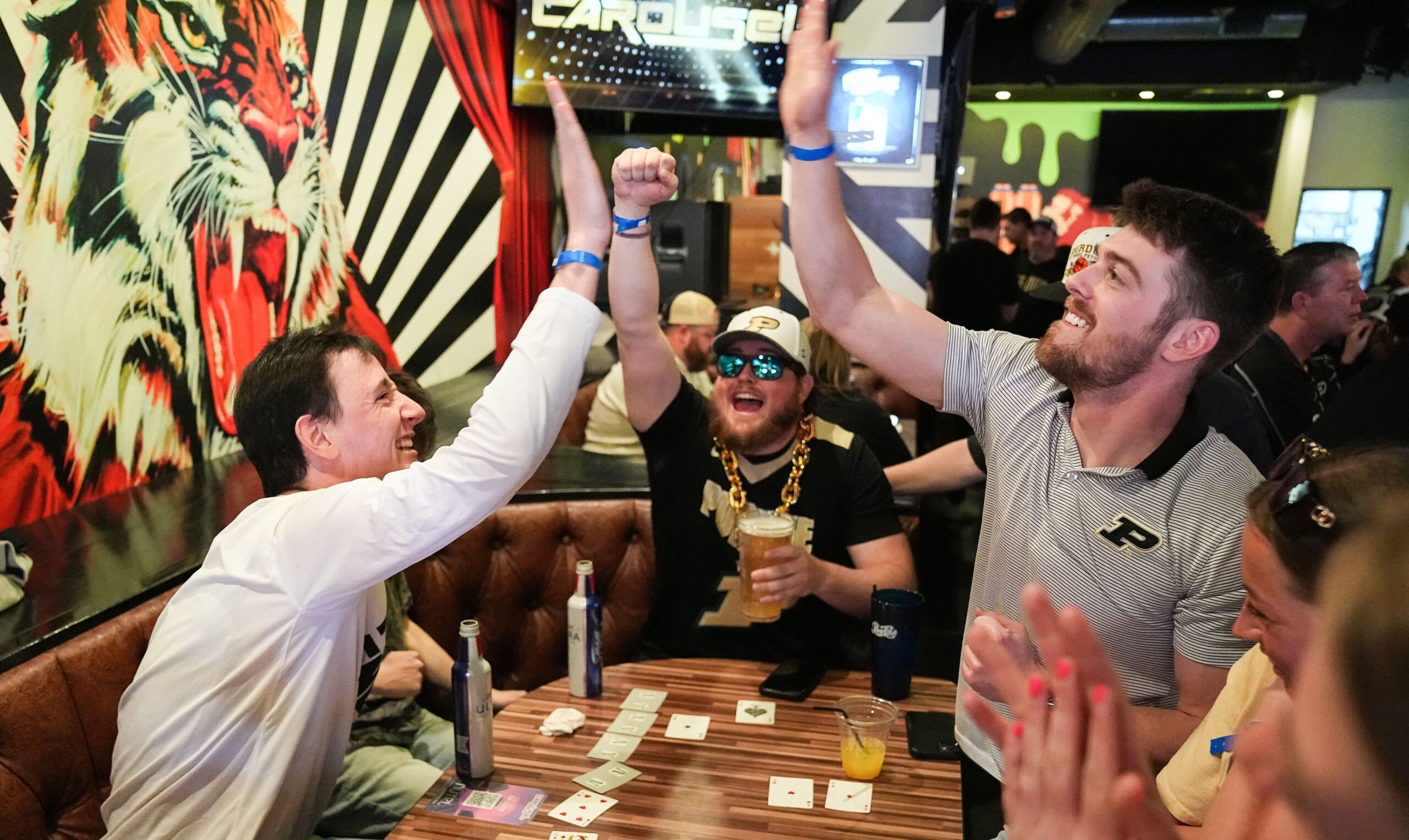 Purdue Boilermakers fans cheer while playing cards during a Boilers in the Stands party at Carousel Bar on Monday, April 8, 2024, ahead of the NCAA Men’s Basketball Tournament Final Four game against Connecticut Huskies at State Farm Stadium in Glendale, Ariz. As the excitement builds, remember that what does the + and - mean in sports betting is very important.